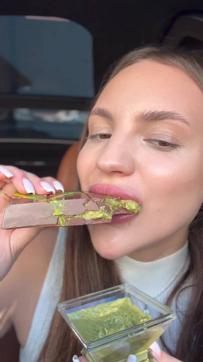 Still from Maria Vehera’s December 2023 TikTok, eating a FIX Dubai chocolate bar in a car with the green pistachio and kataifi filling visible